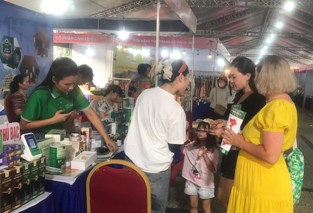 Khách nước ngoài mua sản phẩm OCOP tại điểm khai mạc Tuần lễ Thương mại số và kết nối vùng Đà Nẵng 2025. Ảnh Ngô Anh Văn