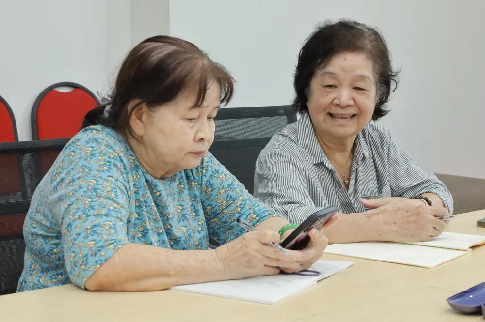 Bà Châu (bìa phải) đang trao đổi cùng học viên chung lớp. Ảnh: DI LINH. Người trẻ tại TPHCM dạy công nghệ, AI miễn phí cho người lớn tuổi