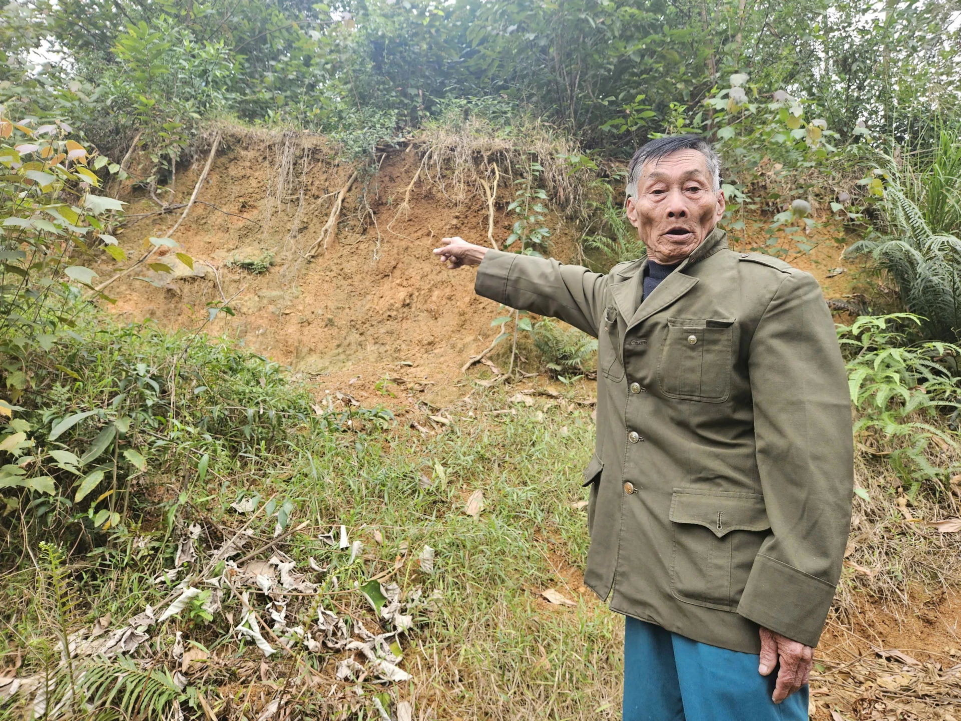 Dự án kè chống sạt lở đồi núi thị trấn Quy Đạt, huyện Minh Hóa cũ: Bao giờ được triển khai thực hiện? 1 Ông Đinh Minh Chế (TDP 8, xã Minh Hóa) chỉ tay về vết nứt, sạt lở đất lớn ở đồi Cây Sường - Ảnh: B.T