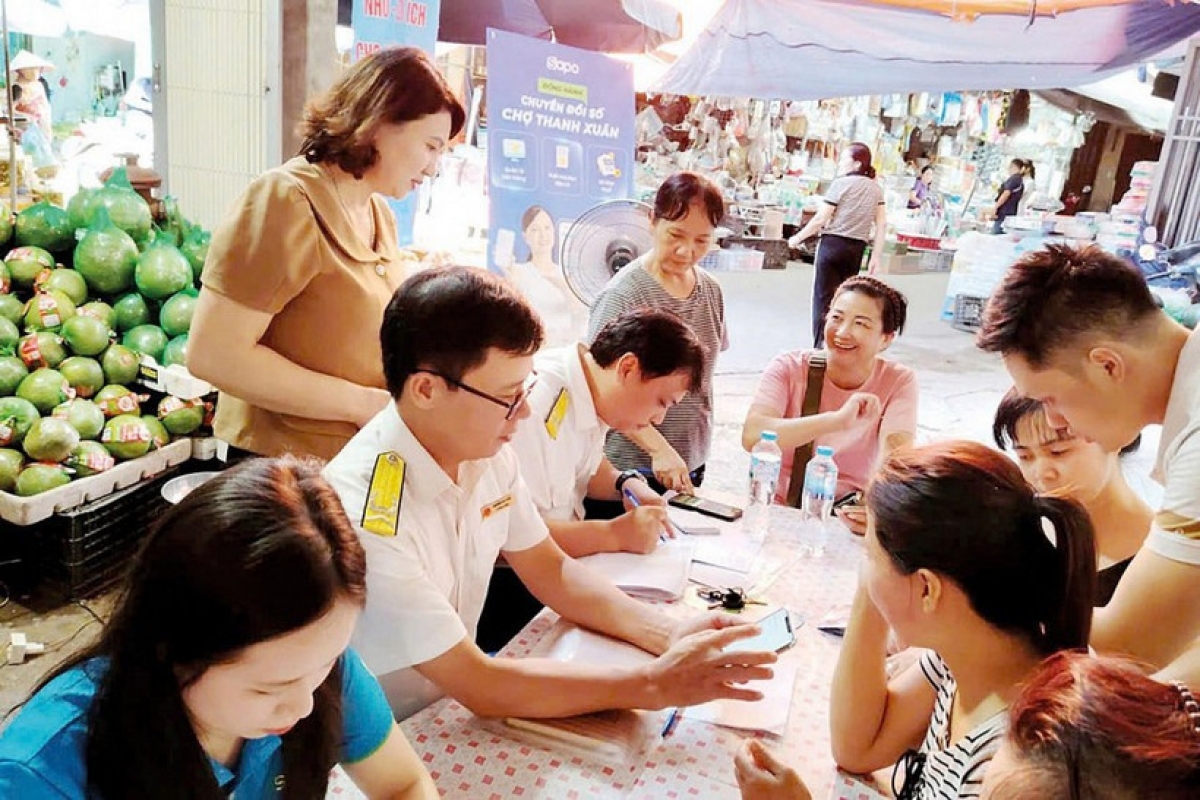 Công chức Thuế TP. Hà Nội hưỡng dẫn hỗ kinh doanh cài đặt, sử dụng etax mobile. Ảnh: KT