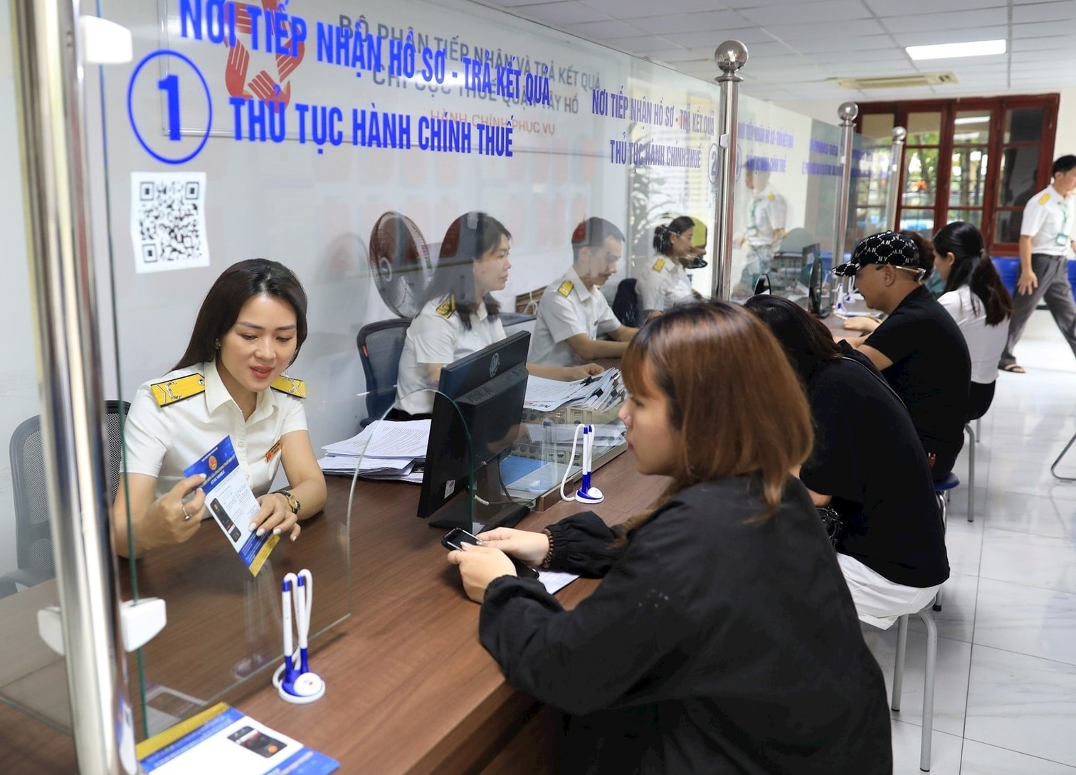 Công chức Thuế TP. Hà Nội hỗ trợ người dân làm thủ tục nộp thuế. Ảnh: KT